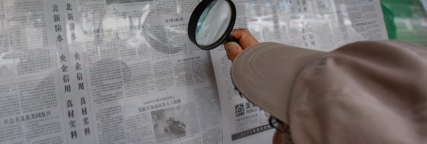 An elderly person reads a newspaper with magnifying glasses that says 'Progress made in the research and development of China's new aircraft carrier' in Beijing, China, 04 August 2022.