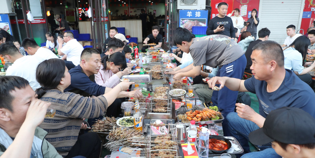 Customers eat skewers at Muyang Village Grill in Zibo, East China's Shandong province