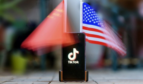 Smartphone showing the Logo of TikTok in front of US and Chinese flags