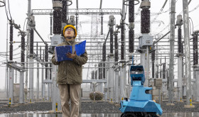 A robot assisted by power personnel makes a snowy inspection of a substation in Taizhou, Jiangsu province, China, December 18, 2023.